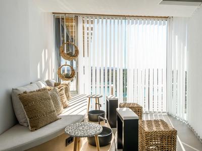 Pièce lumineuse avec banc confortable, tons naturels et rideaux laissant entrer la lumière du jour.