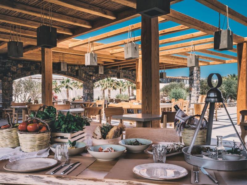 Espace extérieur confortable d'un hôtel avec table dressée et toit en poutres de bois.