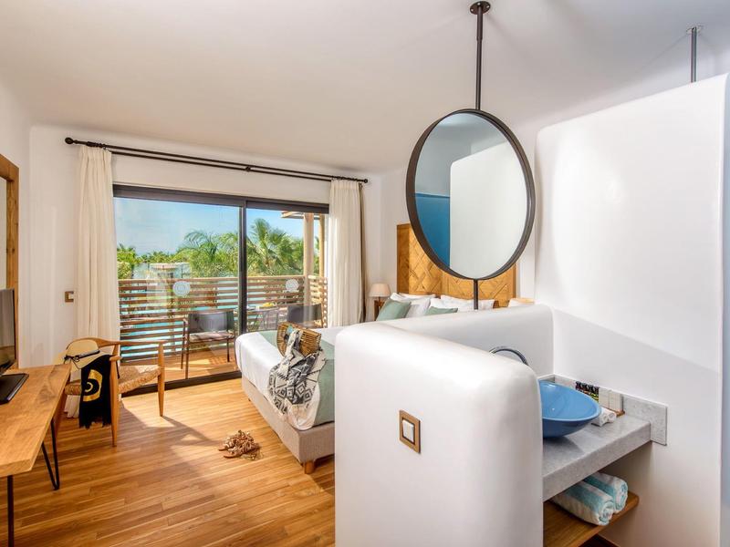 Chambre d'hôtel moderne avec balcon offrant une vue sur un environnement verdoyant.