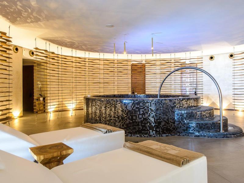 Espace bien-être moderne avec canapés confortables et style jacuzzi sous une lumière chaude.