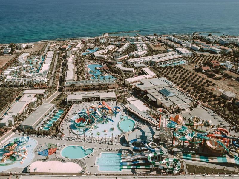 Vue aérienne d'un grand complexe de vacances avec piscines, attractions aquatiques, près de la mer.