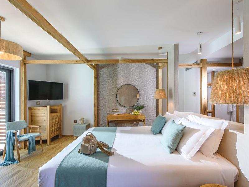 Chambre d'hôtel moderne avec lit double, décoration bois clair et télévision murale.