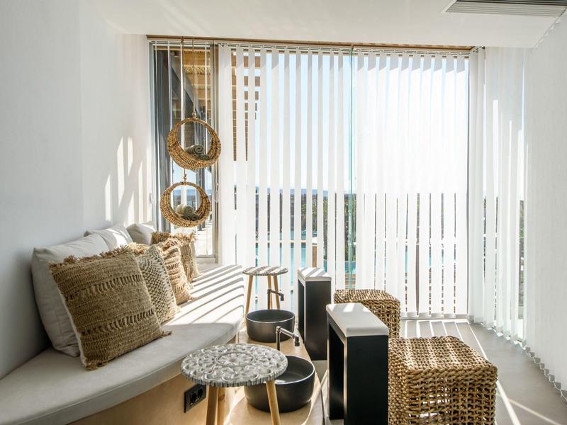 Pièce lumineuse avec banc confortable, tons naturels et rideaux laissant entrer la lumière du jour.