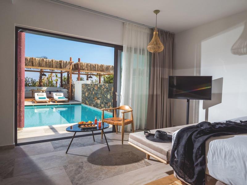 Chambre d'hôtel lumineuse avec accès à une piscine et un espace extérieur avec des transats.