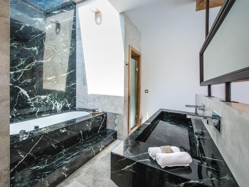 Salle de bain moderne avec baignoire et lavabo en marbre noir, serviette blanche posée.