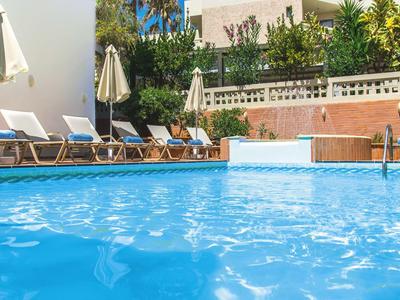 Blue pool with sun loungers and umbrellas on a sunny terrace.