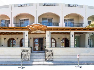 Entrance of a white two-story beach hotel with arches and balconies.