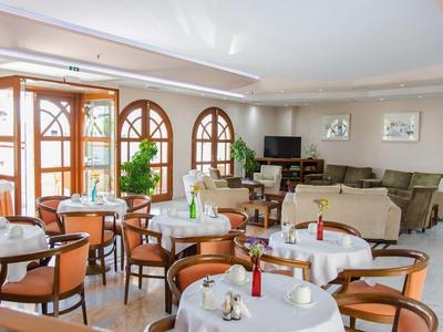 Bright restaurant with tables, chairs, large windows, and flower decorations.