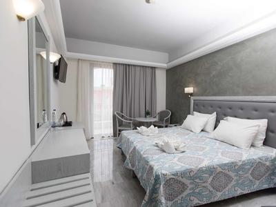 Camera d'hotel moderna con letto matrimoniale, zona soggiorno e balcone con tende.