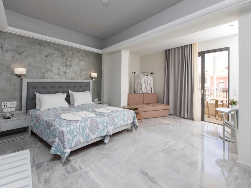 Camera d'hotel luminosa con letto matrimoniale, poltrona e balcone