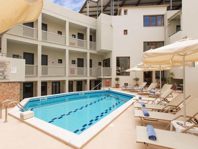 Area piscina esterna moderna con lettini e ombrelloni in un hotel.