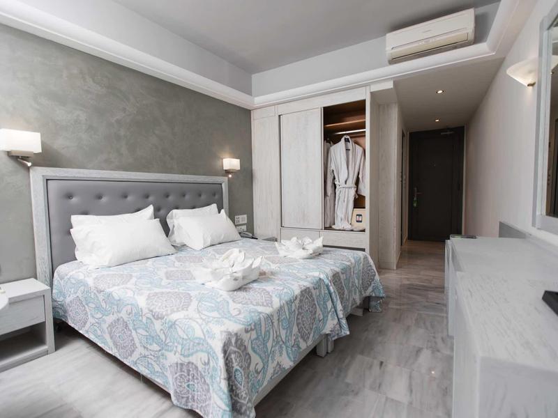 Camera moderna con letto matrimoniale, armadio, aria condizionata e due comodini.