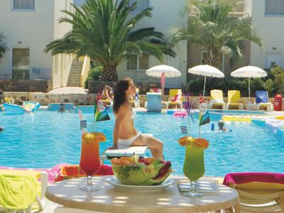 Poolbereich mit Liegestühlen und Getränken, Gäste entspannen am Wasser in sonniger Umgebung.