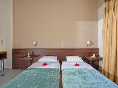 Twee eenpersoonsbedden met blauwe dekens en witte kussens in een hotelkamer met beige gordijnen.