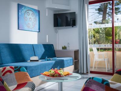 Modern woonkamer met blauwe bank, tv en toegang tot balkon met planten buiten.