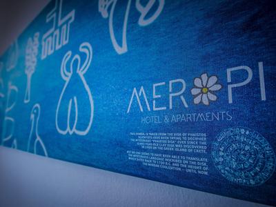 Blaues Schild mit dem Schriftzug 'MEROPI Hotel & Apartments' an einer weißen Wand.
