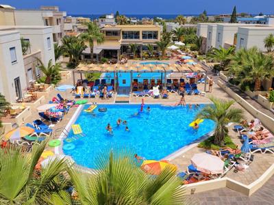 Ein belebter Hotelpool mit vielen Gästen und Sonnenliegen unter klarem blauem Himmel.