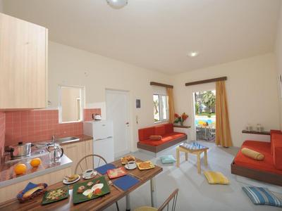 Kleine moderne vakantiewoning met kitchenette, eettafel en twee rode banken.