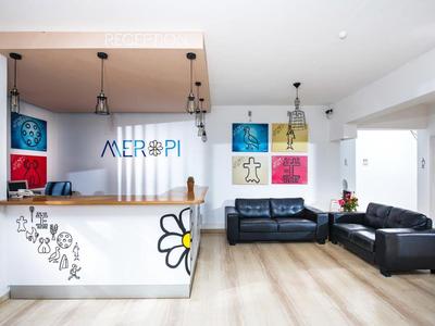 Heller Hotel-Lobby mit Empfangstresen, Sofas und moderner Wanddekoration.