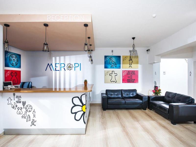 Lichte receptieruimte met houten balie, geschilderde muren en leren banken in een hotel.