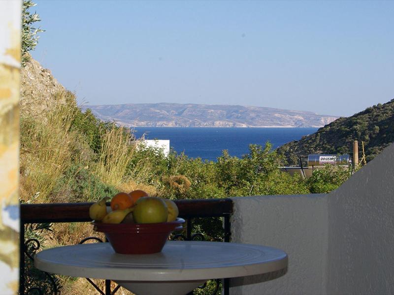 Blick auf das Meer mit Früchteschale auf einem Tisch auf einer Terrasse.