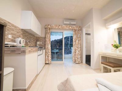 Helles Urlaubszimmer mit Kochnische, Balkon und Ausblick auf die Berge.