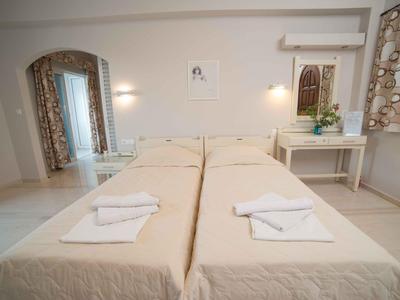 Hell eingerichtetes Hotelzimmer mit zwei Einzelbetten, weißen Handtüchern und Schreibtisch.