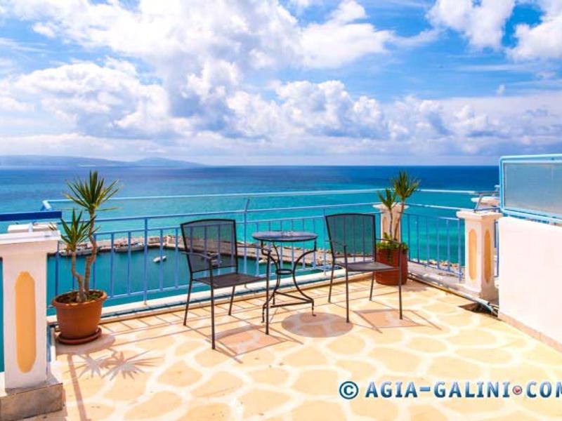 Balkon mit Tisch und Stühlen, Blick auf das blaue Meer und bewölkter Himmel.
