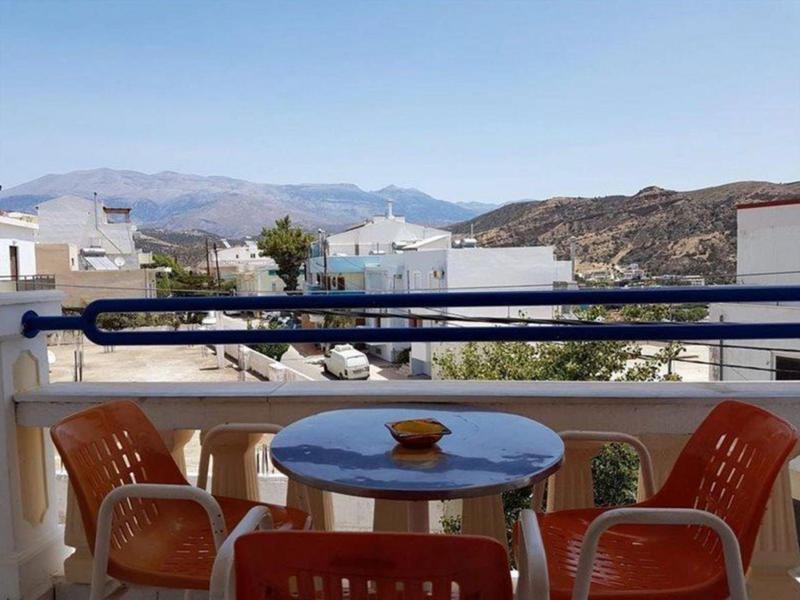 Balkon mit rundem Tisch und vier Stühlen mit Bergblick bei klarem Himmel.