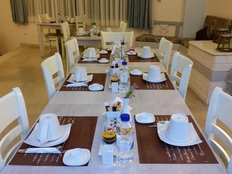 Ein gedeckter Esstisch in einem hellen Raum mit weißen Stühlen und Geschirr.