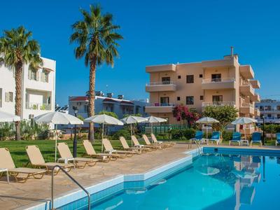 Piscina all'aperto invitante con sdraio e ombrelloni davanti a edifici dell'hotel sotto un cielo limpido.