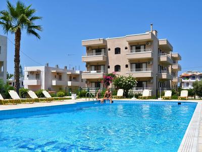 Piscina all'aperto con lettini davanti a edificio alberghiero pluripiano sotto cielo sereno
