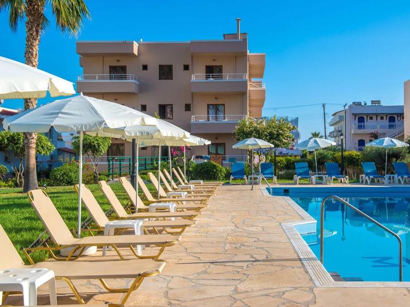 Area piscina vuota con lettini e ombrelloni di fronte a un edificio dell'hotel in una giornata di sole.