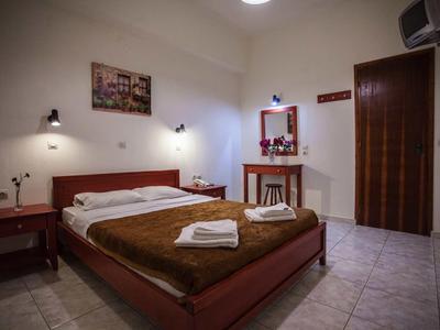 Ein schlichter Hotelzimmer mit einem Doppelbett, Nachttischen, einem Spiegel und gefliesten Boden.