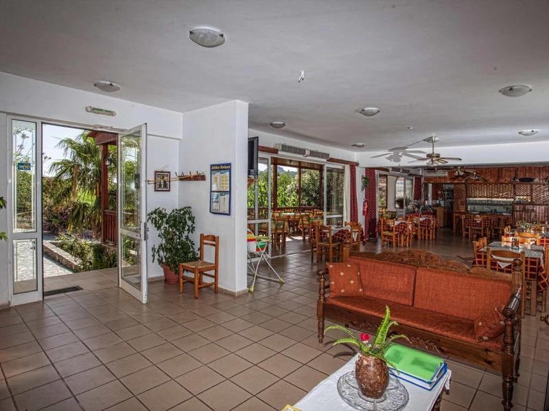 Großer heller Wohnraum mit braunen Holzmöbeln, großen Fenstern und Pflanzen in Töpfen.