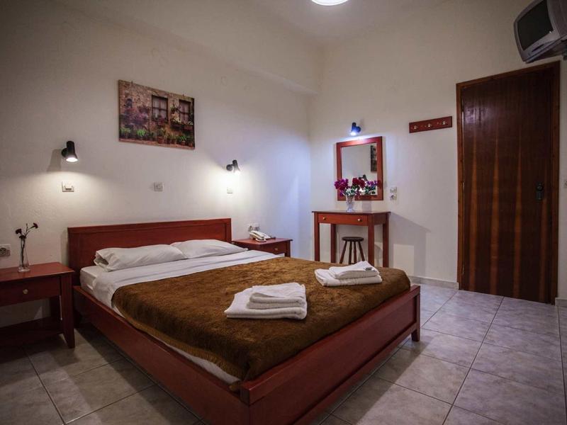 Ein schlichter Hotelzimmer mit einem Doppelbett, Nachttischen, einem Spiegel und gefliesten Boden.