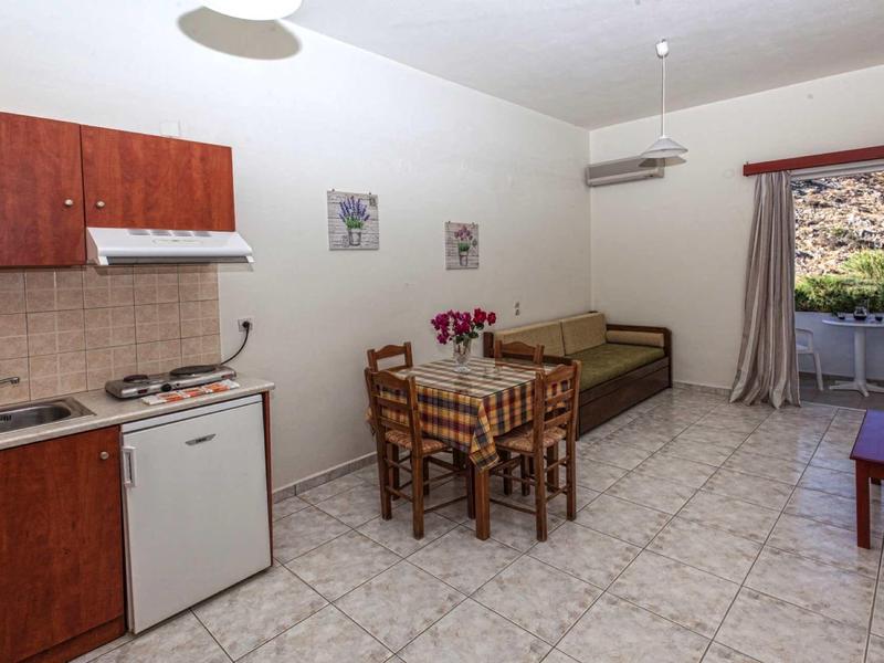 Kleine Küche mit Esstisch und Stühlen, Sofa und Zugang zu Balkon oder Terrasse mit Ausblick.