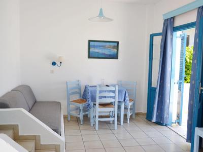 Stanza luminosa con zona pranzo, divano, mobili blu e porta aperta sul giardino.