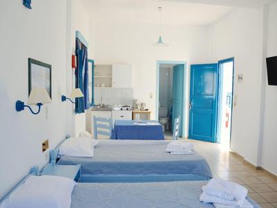 Camera d'hotel luminosa con tre letti singoli, pareti bianche e porte e mobili blu.