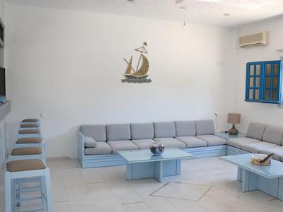 Zona giorno moderna con divano angolare grigio, sgabelli, tavolo blu e finestra con cornice blu.