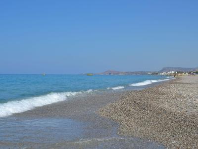 Plage de galets avec des vagues douces et un ciel bleu clair au bord de la mer