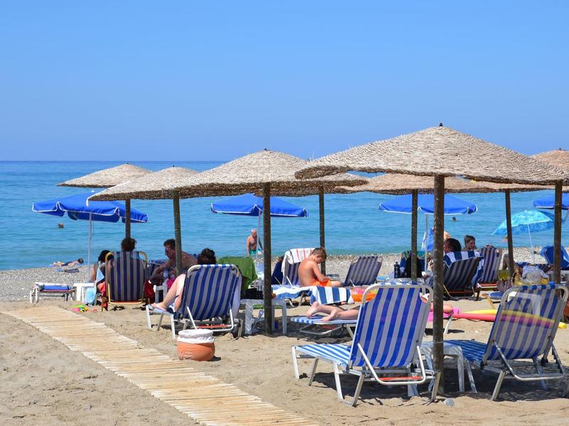 Spiaggia con sdraio e ombrelloni sul mare calmo sotto un cielo limpido.