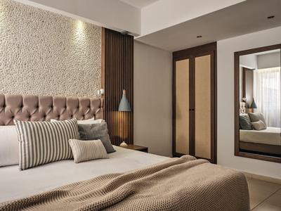 Modernes Schlafzimmer mit braunem Bett, Kissen, Kleiderschrank und großem Spiegel an der Wand.