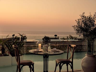 Romantische tafel voor twee met kaars op terras met zeezicht bij zonsondergang.