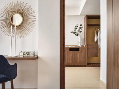 Moderner Flur mit dunklem Holzrahmen, weißem Wandspiegel und blauem Polsterstuhl.