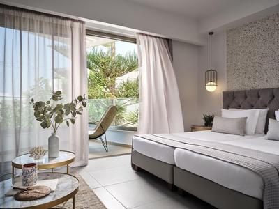 Lichte hotelkamer met twee eenpersoonsbedden, balkon met stoel en uitzicht op planten.