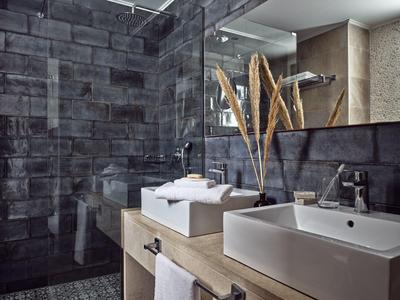 Modernes Badezimmer mit eckiger weißer Keramikspüle, Holzablage und dunklen Wandfliesen.