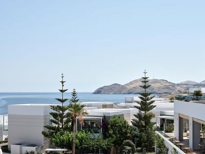 Modern hotel met uitzicht op zee en omliggende heuvels bij heldere hemel.