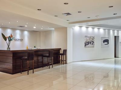 Moderne hotelreceptie met donkerhouten balie, barkrukken en minimalistische kunst.