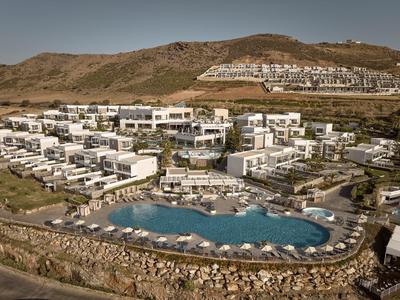 Große Ferienanlage mit weißen Gebäuden, mehreren Pools und umgeben von braunen Hügeln.